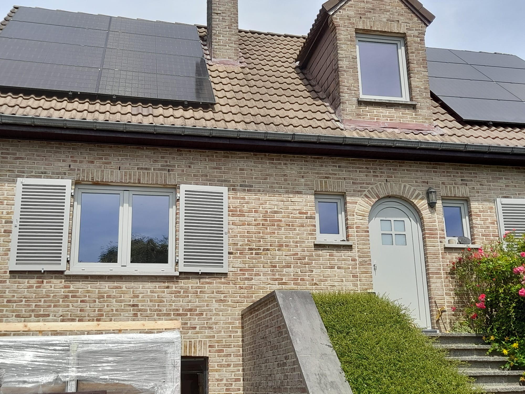 Poseur mesurant une grande fenêtre sur la façade d'une maison